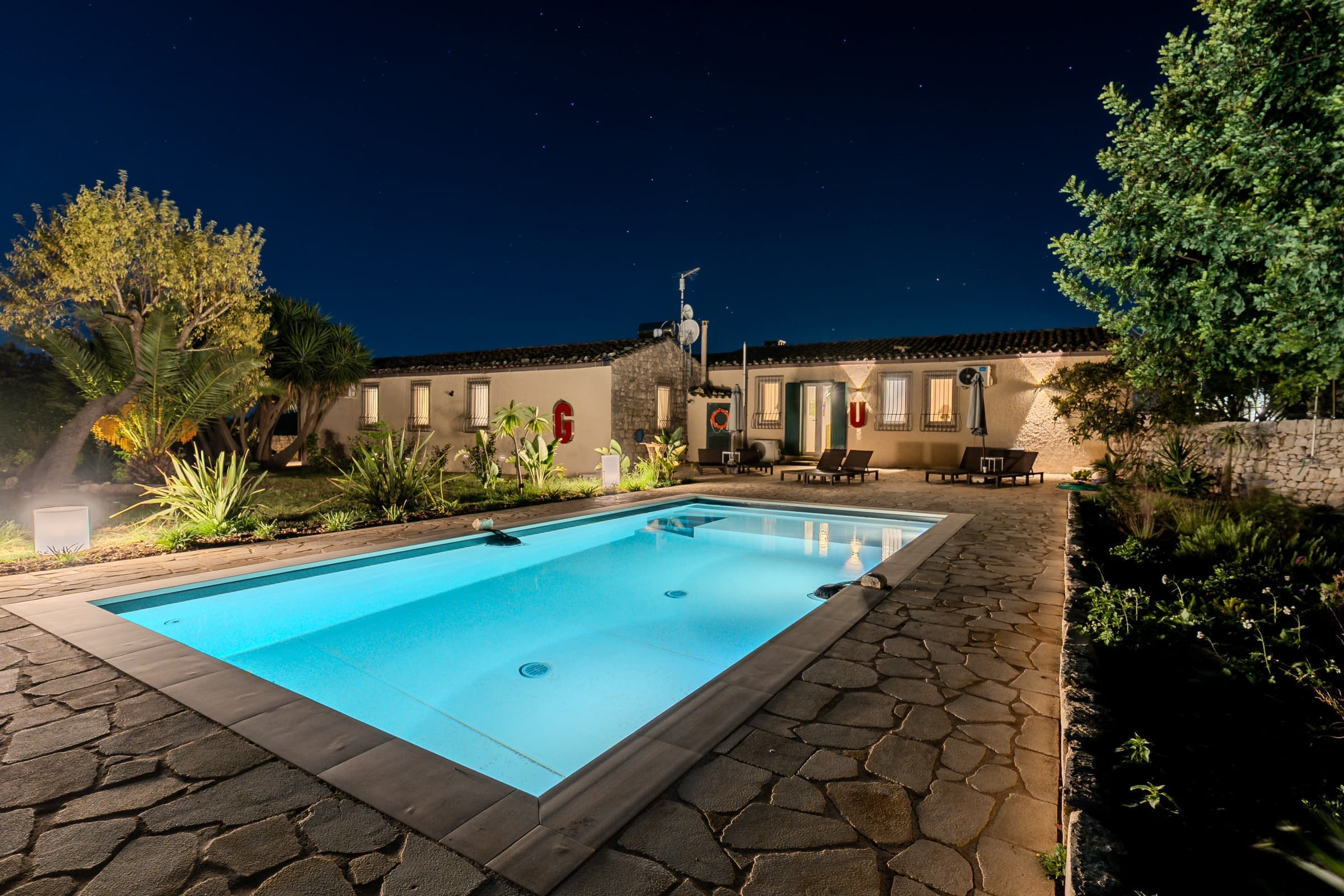 Pool area at night with tropical garden